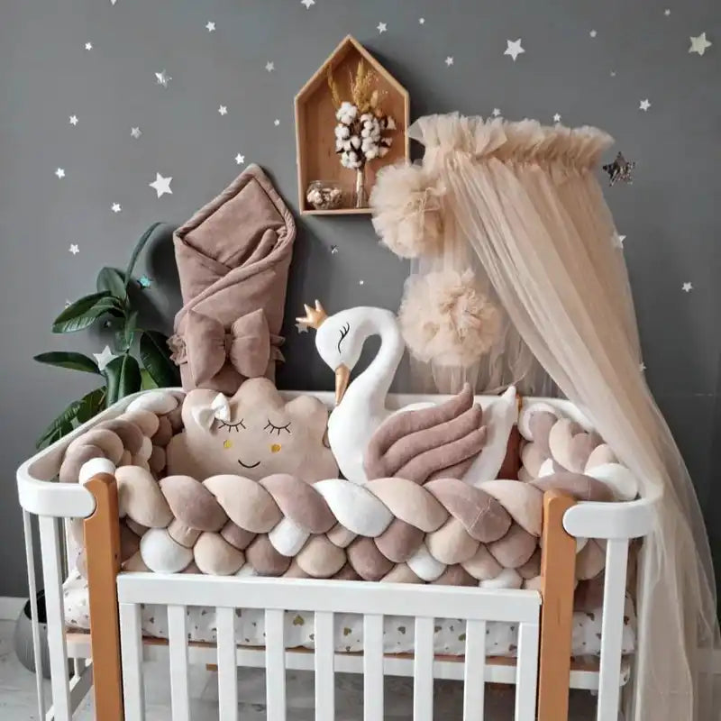 Lit en bois blanc avec des coussins de protection tressés et des décorations de cygne.