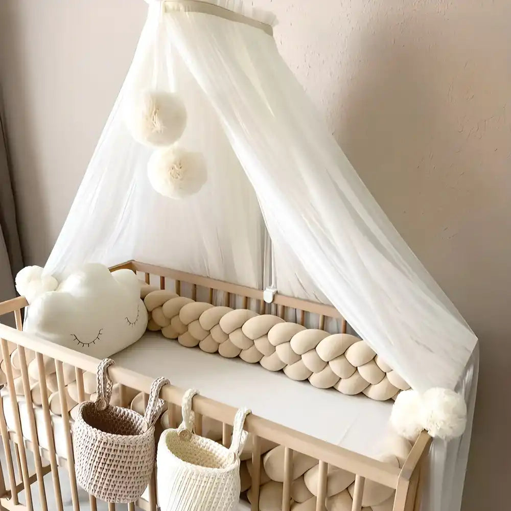 Lit bébé en bois avec baldaquin blanc et protection en cordon tressé.